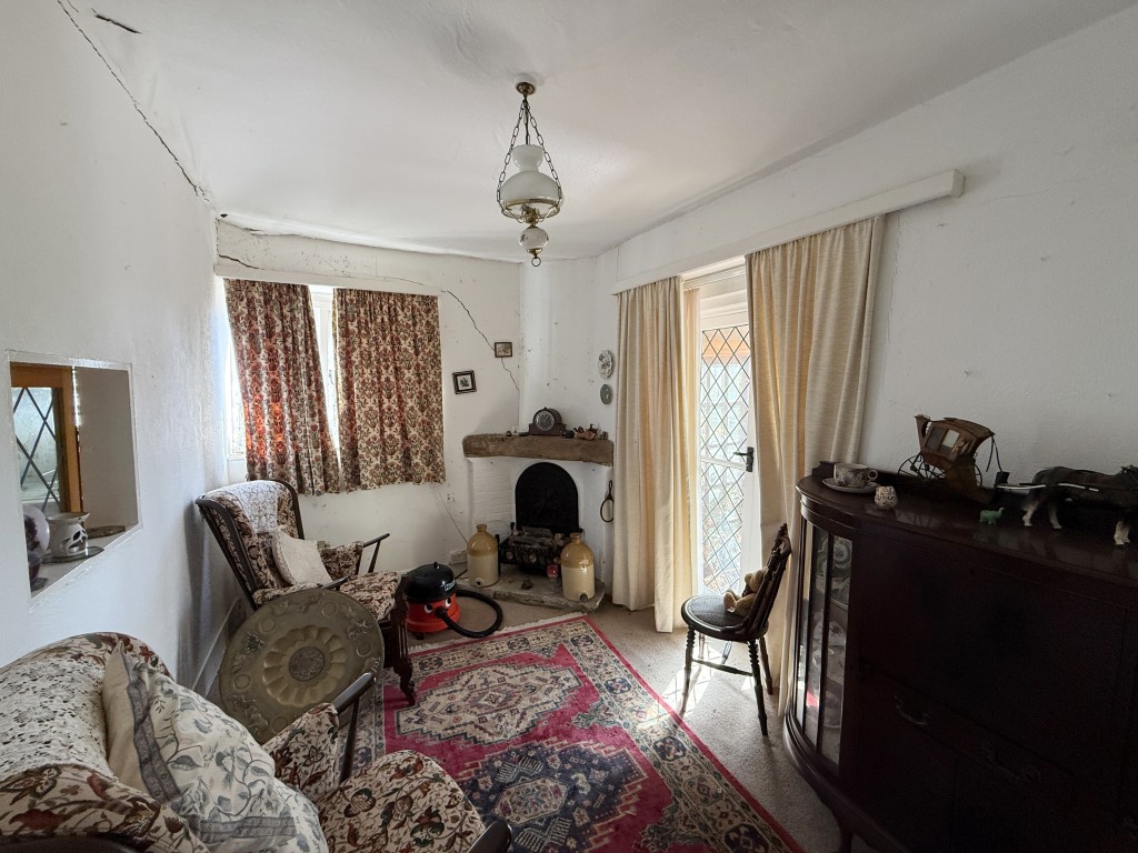 Lot: 52 - STRUCTURALLY DAMAGED DETACHED COTTAGE FOR IMPROVEMENT WITH GARAGE - Living room with doors to conservatory